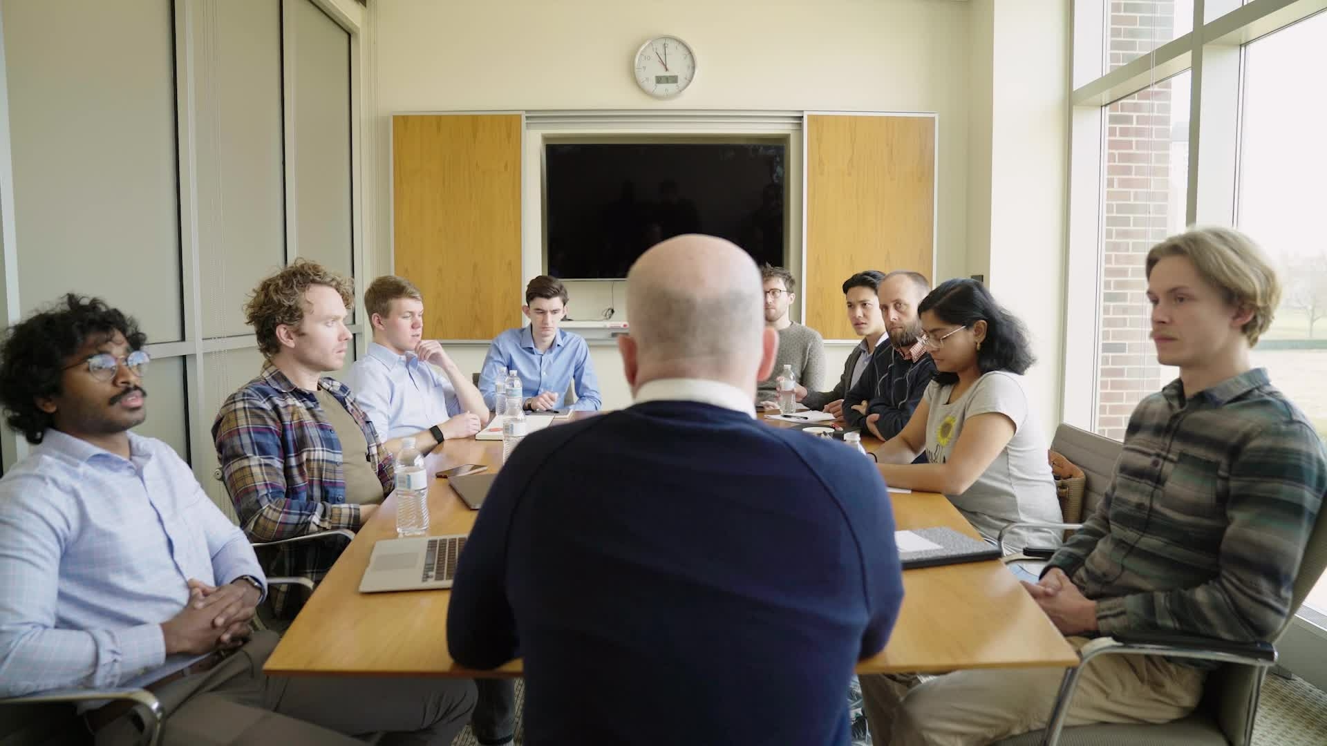 Man sitting at head of table, surrounded by students